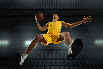 Image showing Young professional basketball player in action, motion isolated on black background, look from the bottom. Concept of sport, movement, energy and dynamic.