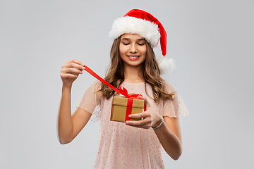 Image showing teenage girl in santa hat opening christmas gift