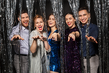 Image showing happy friends in party clothes with tinsel curtain