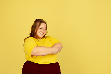 Image showing Beautiful caucasian plus size model isolated on yellow studio background. Concept of inclusion, human emotions, facial expression