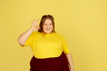 Image showing Beautiful caucasian plus size model isolated on yellow studio background. Concept of inclusion, human emotions, facial expression