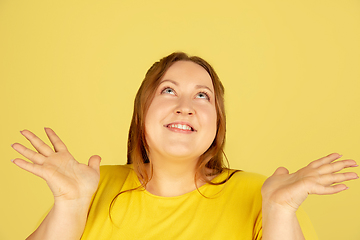 Image showing Beautiful caucasian plus size model isolated on yellow studio background. Concept of inclusion, human emotions, facial expression