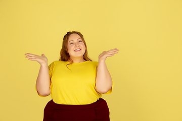 Image showing Beautiful caucasian plus size model isolated on yellow studio background. Concept of inclusion, human emotions, facial expression