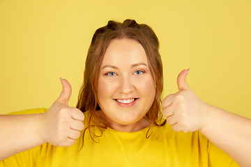 Image showing Beautiful caucasian plus size model isolated on yellow studio background. Concept of inclusion, human emotions, facial expression