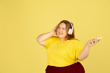 Image showing Beautiful caucasian plus size model isolated on yellow studio background. Concept of inclusion, human emotions, facial expression