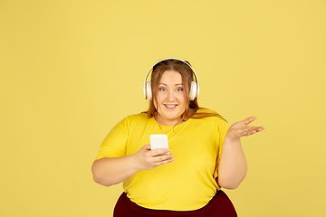 Image showing Beautiful caucasian plus size model isolated on yellow studio background. Concept of inclusion, human emotions, facial expression