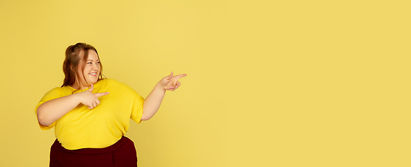 Image showing Beautiful caucasian plus size model isolated on yellow studio background. Concept of inclusion, human emotions, facial expression