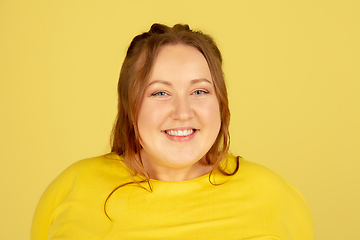 Image showing Beautiful caucasian plus size model isolated on yellow studio background. Concept of inclusion, human emotions, facial expression