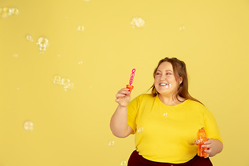 Image showing Beautiful caucasian plus size model isolated on yellow studio background. Concept of inclusion, human emotions, facial expression