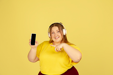 Image showing Beautiful caucasian plus size model isolated on yellow studio background. Concept of inclusion, human emotions, facial expression