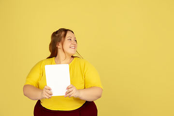 Image showing Beautiful caucasian plus size model isolated on yellow studio background. Concept of inclusion, human emotions, facial expression