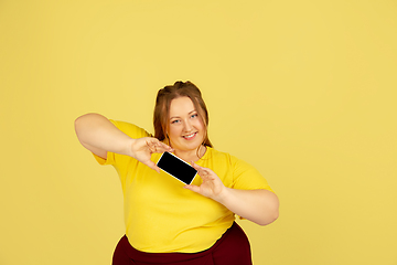 Image showing Beautiful caucasian plus size model isolated on yellow studio background. Concept of inclusion, human emotions, facial expression