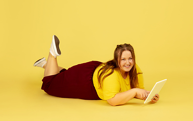 Image showing Beautiful caucasian plus size model isolated on yellow studio background. Concept of inclusion, human emotions, facial expression