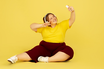 Image showing Beautiful caucasian plus size model isolated on yellow studio background. Concept of inclusion, human emotions, facial expression