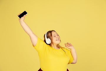 Image showing Beautiful caucasian plus size model isolated on yellow studio background. Concept of inclusion, human emotions, facial expression