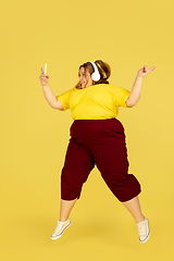 Image showing Beautiful caucasian plus size model isolated on yellow studio background. Concept of inclusion, human emotions, facial expression