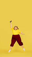 Image showing Beautiful caucasian plus size model isolated on yellow studio background. Concept of inclusion, human emotions, facial expression