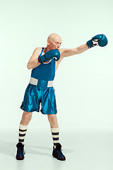 Image showing Senior man wearing sportwear boxing isolated on studio background. Concept of sport, activity, movement, wellbeing. Copyspace, ad.