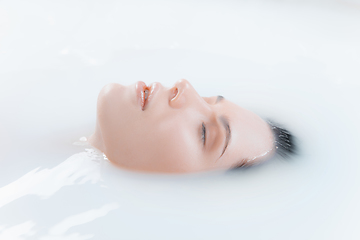 Image showing Close up female face in the milk bath with soft white glowing. Copyspace for advertising. Beauty, fashion, style, bodycare concept.