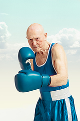 Image showing Senior man wearing sportwear boxing on sky background. Concept of sport, activity, movement, wellbeing. Copyspace, ad.