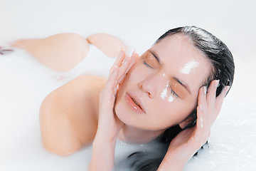 Image showing Close up female model in the milk bath with soft white glowing. Copyspace for advertising. Beauty, fashion, style, bodycare concept.