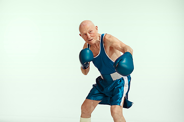 Image showing Senior man wearing sportwear boxing isolated on studio background. Concept of sport, activity, movement, wellbeing. Copyspace, ad.