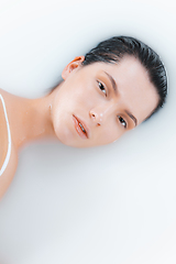 Image showing Close up female face in the milk bath with soft white glowing. Copyspace for advertising. Beauty, fashion, style, bodycare concept.