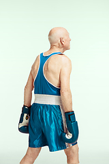 Image showing Senior man wearing sportwear boxing isolated on studio background. Concept of sport, activity, movement, wellbeing. Copyspace, ad.