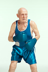 Image showing Senior man wearing sportwear boxing isolated on studio background. Concept of sport, activity, movement, wellbeing. Copyspace, ad.