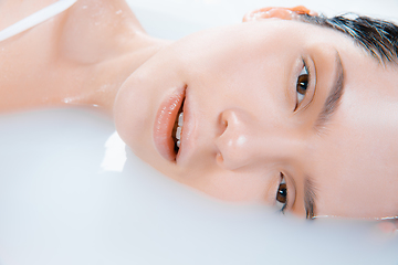 Image showing Close up female face in the milk bath with soft white glowing. Copyspace for advertising. Beauty, fashion, style, bodycare concept.