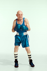 Image showing Senior man wearing sportwear boxing isolated on studio background. Concept of sport, activity, movement, wellbeing. Copyspace, ad.