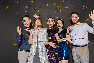 Image showing happy friends at party under confetti over black