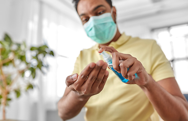 Image showing close up of man in mask applying hand sanitizer