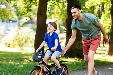 Image showing father teaching little son to ride bicycle at park