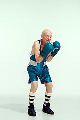 Image showing Senior man wearing sportwear boxing isolated on studio background. Concept of sport, activity, movement, wellbeing. Copyspace, ad.