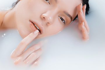 Image showing Close up female face in the milk bath with soft white glowing. Copyspace for advertising. Beauty, fashion, style, bodycare concept.