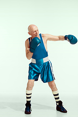 Image showing Senior man wearing sportwear boxing isolated on studio background. Concept of sport, activity, movement, wellbeing. Copyspace, ad.