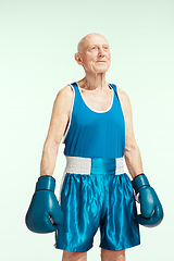 Image showing Senior man wearing sportwear boxing on sky background. Concept of sport, activity, movement, wellbeing. Copyspace, ad.