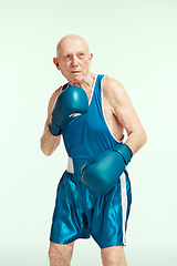 Image showing Senior man wearing sportwear boxing isolated on studio background. Concept of sport, activity, movement, wellbeing. Copyspace, ad.