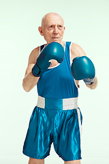 Image showing Senior man wearing sportwear boxing isolated on studio background. Concept of sport, activity, movement, wellbeing. Copyspace, ad.