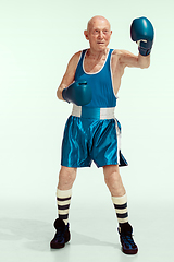 Image showing Senior man wearing sportwear boxing isolated on studio background. Concept of sport, activity, movement, wellbeing. Copyspace, ad.