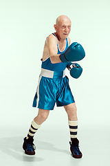 Image showing Senior man wearing sportwear boxing isolated on studio background. Concept of sport, activity, movement, wellbeing. Copyspace, ad.