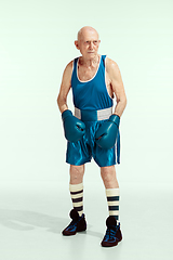 Image showing Senior man wearing sportwear boxing isolated on studio background. Concept of sport, activity, movement, wellbeing. Copyspace, ad.