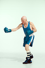 Image showing Senior man wearing sportwear boxing isolated on studio background. Concept of sport, activity, movement, wellbeing. Copyspace, ad.