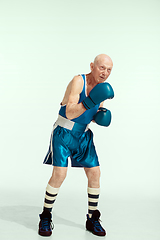 Image showing Senior man wearing sportwear boxing isolated on studio background. Concept of sport, activity, movement, wellbeing. Copyspace, ad.