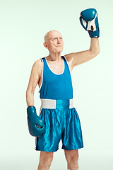 Image showing Senior man wearing sportwear boxing isolated on studio background. Concept of sport, activity, movement, wellbeing. Copyspace, ad.