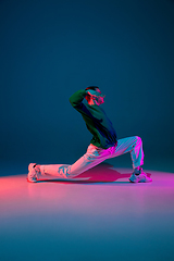 Image showing Stylish sportive boy dancing hip-hop in stylish clothes on colorful background at dance hall in neon light. Youth culture, movement, style and fashion, action.