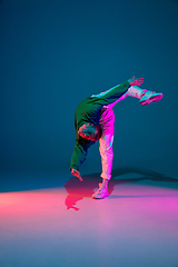 Image showing Stylish sportive boy dancing hip-hop in stylish clothes on colorful background at dance hall in neon light. Youth culture, movement, style and fashion, action.