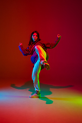 Image showing Stylish sportive girl dancing hip-hop in stylish clothes on colorful background at dance hall in neon light. Youth culture, movement, style and fashion, action.