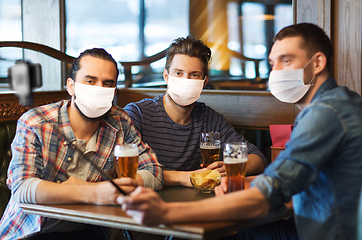 Image showing men in masks take selfie and drink beer at bar